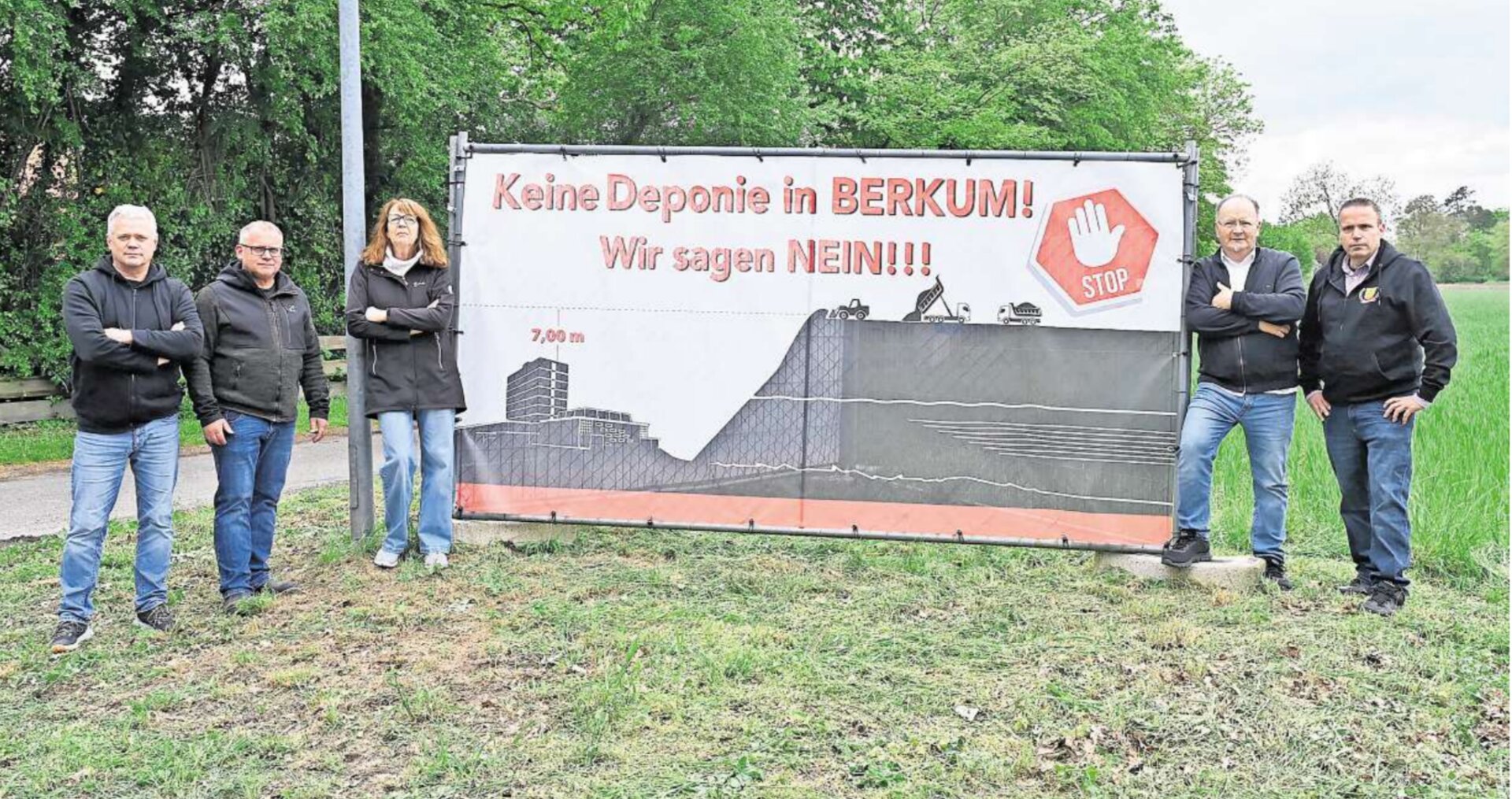 Fünf Mitglieder der Bürgerinitiative stehen vor ihrem Protest-Banner an der B65 bei Berkum. Auf dem Banner steht „Keine Deponie in BERKUM! Wir sagen NEIN!!!